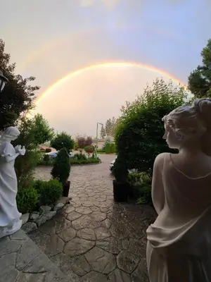 a rainbow in the sky with a statue in a garden at Villa Bellissimo FranTalia - Résidence & Galleriséum in Kelowna