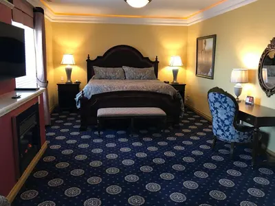a bedroom with a bed and a chair and a television at Chateau Louis Hotel & Conference Centre in Edmonton
