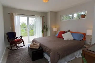 a bedroom with a large bed and a window at Halfmoon Haven Beach Cottage or Oceanview Suite in Halfmoon Bay
