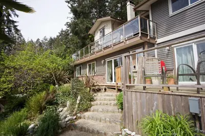 a house with a deck and stairs leading up to it at Halfmoon Haven Beach Cottage or Oceanview Suite in Halfmoon Bay