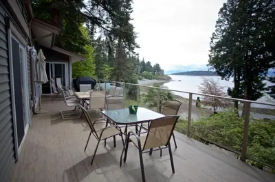 a balcony with tables and chairs and a view of the water at Halfmoon Haven Beach Cottage or Oceanview Suite in Halfmoon Bay