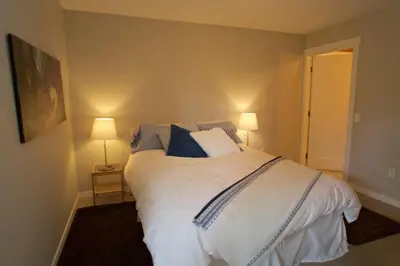 a bedroom with a large white bed with blue pillows at Halfmoon Haven Beach Cottage or Oceanview Suite in Halfmoon Bay
