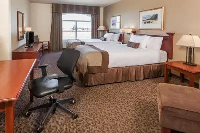 a hotel room with two beds and a desk and a chair at Wingate by Wyndham - Edmonton West in Edmonton