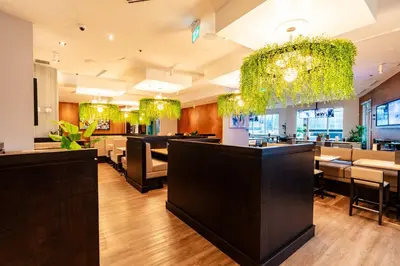 a restaurant with a bar with chairs and plants at Sandman Signature Langley Hotel in Langley