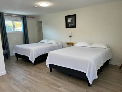 two beds in a room with white sheets at Empire Motel in Penticton