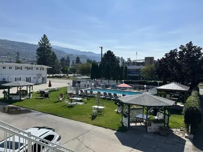 a resort with a swimming pool and tables and chairs at Empire Motel in Penticton