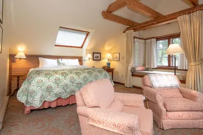 a bedroom with a large bed and two chairs at Hastings House Country House Hotel in Ganges