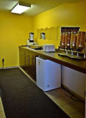 a kitchen with yellow walls and a white refrigerator at Centre Suite Inns Motel in Bonnyville