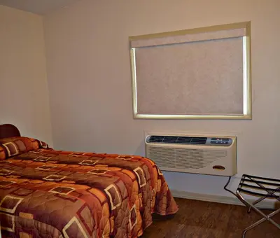 a bedroom with a bed and a window and a fan at Centre Suite Inns Motel in Bonnyville