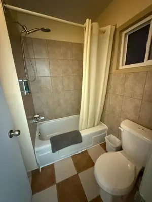 a bathroom with a toilet and a shower and a tub at Centre Suite Inns Motel in Bonnyville