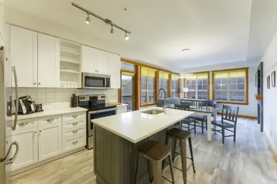 a kitchen with white cabinets and a island with bar stools at Predator Ridge Resort in Vernon