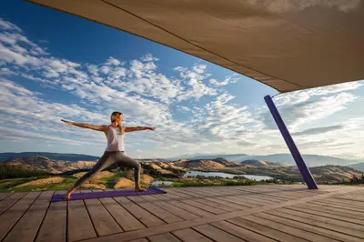 a woman doing yoga on a yoga mat on a deck at Predator Ridge Resort in Vernon