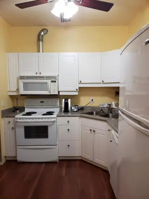 a kitchen with white cabinets and a stove and a sink at Travelodge by Wyndham Spruce Grove in Spruce Grove
