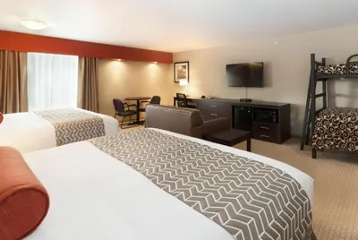 a hotel room with two beds and a flat screen tv at The Kanata Inns Invermere in Invermere