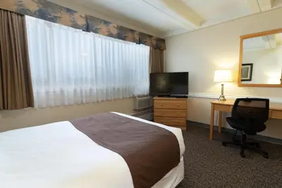 a hotel room with a bed and a desk and a television at BCM Inns Fort McMurray - Downtown in Fort McMurray
