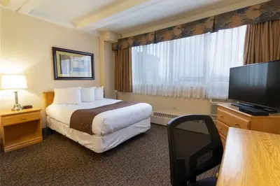 a hotel room with a bed and a flat screen tv at BCM Inns Fort McMurray - Downtown in Fort McMurray