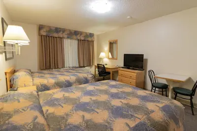 a hotel room with two beds and a desk at Best Maple Inn - Drayton Valley in Drayton Valley