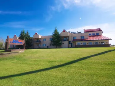 a large building with a grass field in front of it at Best Maple Inn - Drayton Valley in Drayton Valley