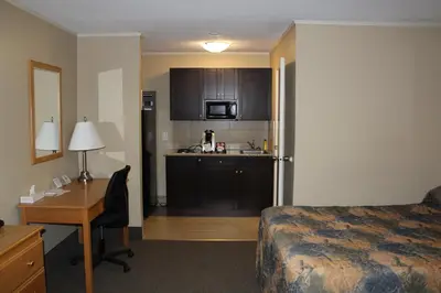 a hotel room with a bed and a desk and a kitchen at Best Maple Inn - Drayton Valley in Drayton Valley