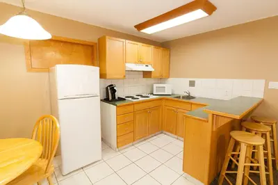 a kitchen with a white refrigerator and wooden cabinets at Best Maple Inn - Drayton Valley in Drayton Valley
