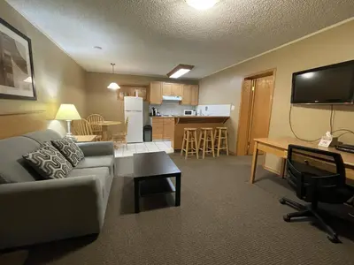 a living room with a couch and a table and a kitchen at Best Maple Inn - Drayton Valley in Drayton Valley