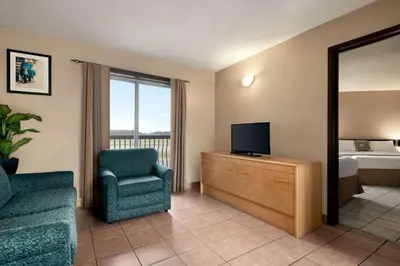 a living room with a tv and a chair and a bedroom at Thriftlodge Edmonton in Edmonton