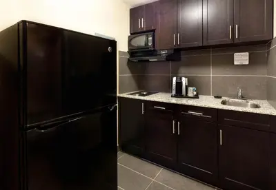 a kitchen with a black refrigerator and a sink at BCMInns - Peace River in Peace River