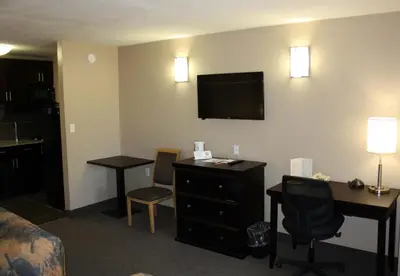 a hotel room with a desk and a tv on the wall at BCMInns - Peace River in Peace River