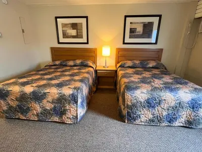 a hotel room with two beds and a lamp at BCMInns - Peace River in Peace River