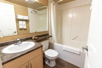 a bathroom with a sink and a toilet and a mirror at BCMInns - Fort McMurray - Rusty's in Fort McMurray