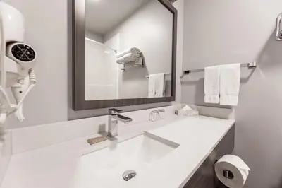 a white bathroom with a sink and a mirror at The Kanata by BCMInns - Hinton in Hinton