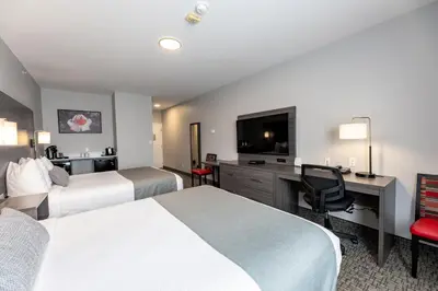 a hotel room with two beds and a desk and a television at The Kanata by BCMInns - Hinton in Hinton
