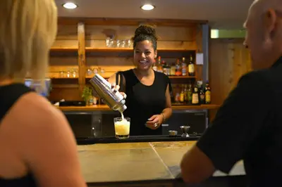 a woman pouring a drink at a bar at Red Tree Lodge in Fernie