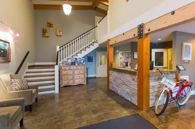a living room with a staircase and a bike in the middle at Red Tree Lodge in Fernie