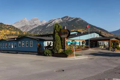 a building with a stop sign and mountains in the background at Red Tree Lodge in Fernie