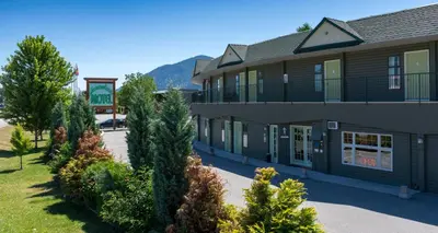 a large building with trees in front of it at Summerland Motel in Summerland