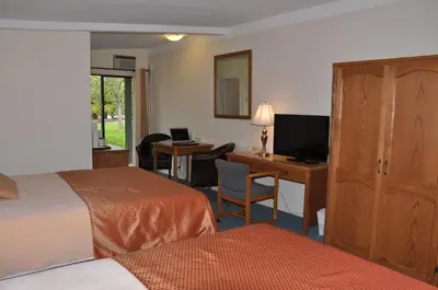 a hotel room with two beds and a desk with a computer at Summerland Motel in Summerland
