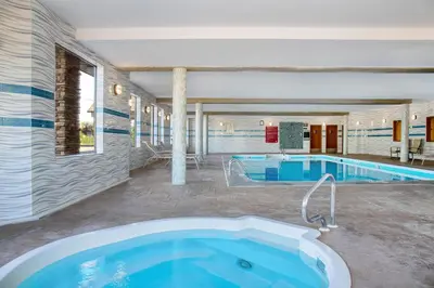 a large bathroom with a tub and a swimming pool at Days Inn & Suites by Wyndham West Edmonton in Edmonton