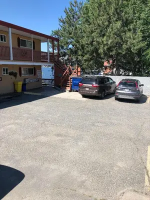 two cars parked in a parking lot in front of a building at Sun Beach Motel in Osoyoos