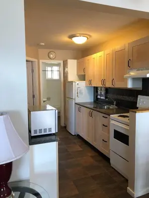 a kitchen with white appliances and wooden cabinets at Sun Beach Motel in Osoyoos
