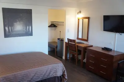 a hotel room with a bed and a desk and a television at Westward Inn & Suites in Langley