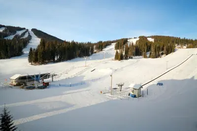 a snow covered ski slope with a ski lift at Sundance Lodge in Sun Peaks