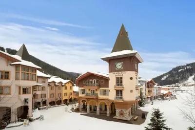 a building with a clock tower in a snow covered town at Sundance Lodge in Sun Peaks