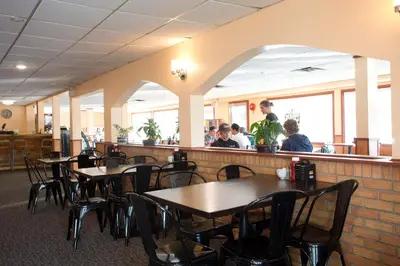 a restaurant with tables and chairs and people sitting at a counter at Valemount Vacation Inn in Valemount