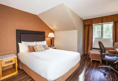 a hotel room with a bed and a desk and a chair at Coast Hillcrest Hotel in Revelstoke