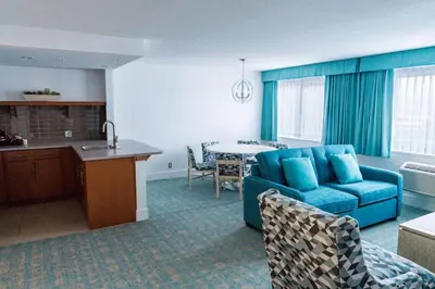 a living room with a blue couch and a kitchen at Coast Hotel & Convention Centre in Langley
