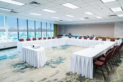 a room with white tables and chairs and windows at Coast Hotel & Convention Centre in Langley