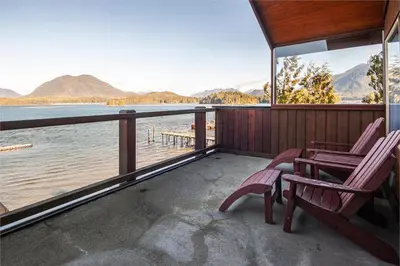 a porch with two chairs and a view of a lake at Himwitsa Lodge in Tofino