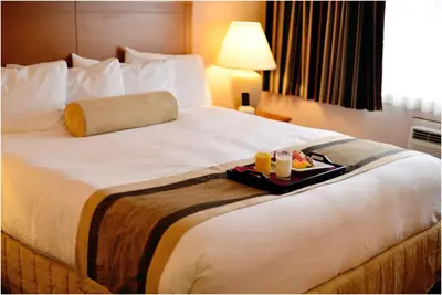 a hotel room with a bed with a tray of food on it at The Hospitality Inn in Port Alberni