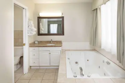 a white bathroom with a tub and a sink at Travelodge by Wyndham Golden Sportsman Lodge in Golden